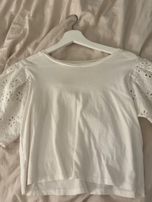 Vit topp - Säljer denna jättegulliga vita toppen med blomdetaljer på ärmarna, använd få gånger🤍