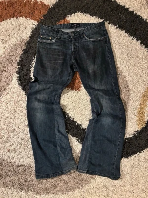 Bootcut Jeans Remade - Laid out liggandes: 	•	Längd: 100 	•	Midja: 42 cm 	•	Innerbenslängd: 26 cm 	•	Nedre bredd (vid benslutet): 25 cm  Kondition: 7/10  Fraktar samma dag eller dagen efter✅  swag rap streetwear baggy vintage skate hiphop y2k affliction archive underground avant garde japan style OG 2000s flared washed affliction jeans drip oldmoney denim