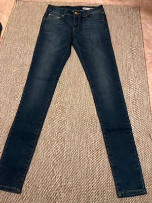 Mörkblå skinny jeans  - Säljer ett par mörkblå skinny jeans. Skulle säga att Jeansen är Mid-Low waist. Hela jeansens längd är ungefär 102 cm. Aldrig använt och är som ny.😊