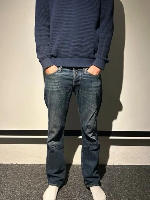 Replay jeans herr - Säljer ett par klassiska med bootcut passform. Jeansen har fem fickor, normal midja och snygga slitningar för en avslappnad look. Tillverkade i tåligt denim. Jeansen är använda men fortfarande i bra skick