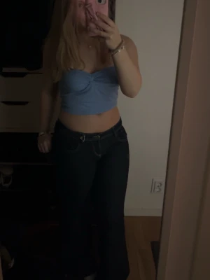 Ljusblå croppad bandeau topp - Säljer en ljusblå croppad bandeau topp med twistad detalj framtill. Toppen är ärmlös och har en enkel, stilren look som passar perfekt till jeans eller kjol. Materialet känns mjukt och stretchigt, vilket gör den bekväm att bära hela dagen.