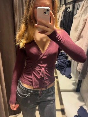 Vinröd wraptop från Zara - Säljer en vinröd wraparound top från Zara med långa ärmar och knyt i midjan. Toppen har en djup v-ringning och är figurnära med croppad passform. Det är väldigt stretchig så jag skulle säga att den passar allt från small till large. Använd ett få tal gånger. Inga defekter. Skriv gärna om frågor!💕