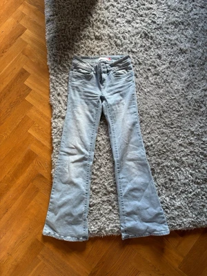 Ljusblå bootcut jeans med rosa söm - Säljer ett par ljusblå bootcut jeans. Jeansen har klassisk femficksmodell och snygga rosa broderade detaljer på bakfickorna. Använda 2 gånger bara