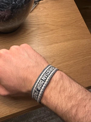 Blå och vit Christian Dior armband - Säljer ett snyggt armband från Christian Dior med texten 'J'ADIOR' broderat i vitt på blå botten. Armbandet har justerbara tofsar i ändarna och är gjort i ett mjukt, vävt material. Perfekt accessoar för att lyfta din outfit. Har används 2-3 gånger, pris kan diskuteras!