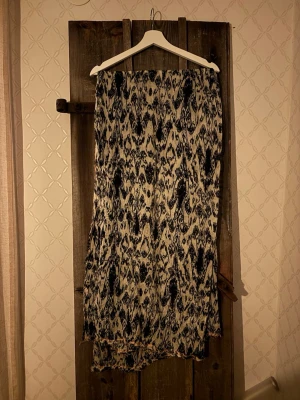 Mönstrad sjal från Pieces - Säljer en lång, beige och marinblå sjal från Pieces med ett unikt mönster som påminner om zebra. Sjalen är tillverkad i ett lätt och luftigt material som känns skönt mot huden. Perfekt för att lyfta vilken outfit som helst med en cool touch.