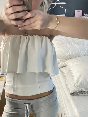Vit bandeau tubtopp med volang - Säljer denna populära superfina topp från Zara. Vit bandou topp med volang❣️, endast andvänd en gång. skriv om du har några frågor och pris kan diskuteras ❣️❣️