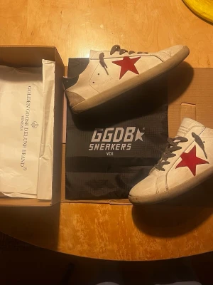 Golden goose superstar  - Säljer ett par väldigt snygga golden goose skor i storlek 46 med en röd stjärna. De är använda men i bra skick, trasiga vid sulan som ni ser på bild 2. Priset är inte hugget i sten!! Kom gärna med bytesförslag också ✌️