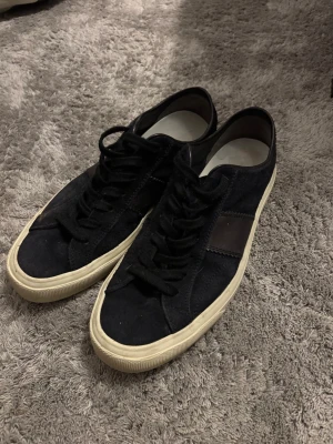Marinblå sneakers från Tom Ford mocka - Säljer ett par marinblåa Tom Ford sneakers i mocka med vita sulor och diskret logga bak på hälen. Skorna har snörning, rund tå och detaljer i marinblå skinn på sidan. Klassisk och stilren modell som passar till det mesta. Ingen box!