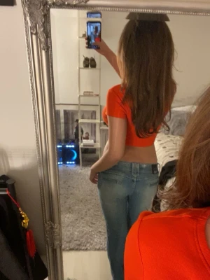 Orange croppad topp från Monki - Säljer en snygg orange croppad topp från Monki i ribbad bomull. Toppen har korta ärmar och rund halsringning, perfekt för dig som gillar färgstarka och trendiga plagg. Passar till jeans eller kjol för en cool look.