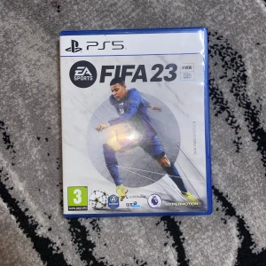 FIFA 23 PS5 - FIFA 23 till PlayStation 5 i mycket fint skick. Komplett med fodral och skiva, inga synliga repor eller skador. Upplev den senaste fotbollssimuleringen med Hypermotion-teknik och över 25 ligor. Perfekt för fotbollsfans och samlare.