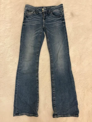 Blå lowwaist bootcut jeans Gina Tricot 158 - Snygga blå jeans från Gina Tricot i storlek 158. Modellen har klassisk femficksdesign, normal passform och bootcut-ben. Low waist