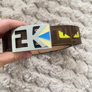 Brunt bälte med mönster från Fendi - Snyggt brunt bälte från Fendi med ett unikt mönster och en iögonfallande spänne i silver med färgglada detaljer. 