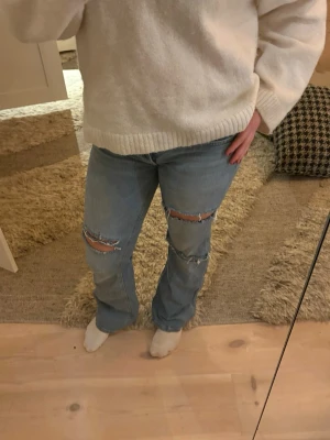 Ljusblå slitna jeans med hål - Säljer ett par ljusblå jeans med bootcut. Köptes från lagar 157 och hålen har jag gjort själv. Lite slitningar nedtill annars bra skick. 
