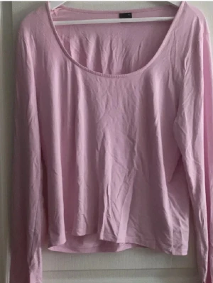 Ljusrosa långärmad topp Gina Tricot - Enkel och mjuk ljusrosa långärmad topp från Gina Tricot. Toppen har rundad, djup urringning och är gjord i ett tunt bomullstyg. Perfekt att styla med jeans eller kjol för en chill look.