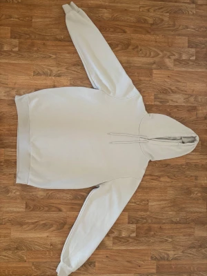 Ljusbeige hoodie från SMOG, storlek L - Säljer en stilren ljusbeige hoodie från SMOG i storlek L. Tröjan har huva med snörning och är tillverkad i mjuk bomullsmix med fleece på insidan. Regular fit och långa ärmar med ribbade muddar. Perfekt för chill dagar eller när du vill ha det extra bekvämt.