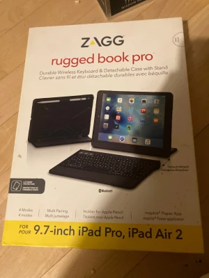 ZAGG Rugged Book Pro för 9.7-inch iPad Pro/iPad Air 2 - Slitstarkt trådlöst tangentbord och avtagbart fodral med ställ, kompatibelt med 9.7-tums iPad Pro och iPad Air 2. Bluetooth, 4 lägen, Apple Pencil-hållare, stöttåligt. Tangentbordet ser ut att vara i gott skick utan synliga defekter.