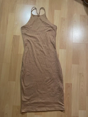 Beige ribbad klänning från Gina Tricot - Beige ribbad klänning från Gina Tricot i storlek XS. Klänningen är figurnära med smala axelband. Materialet är mjukt och stretchigt.