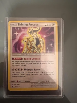 Shining Arceus - Shining Arceus är ett samlarkort från Pokémon-serien med en unik och glänsande design. Perfekt för dig som älskar Pokémon och vill ha något speciellt i din samling! Kortet har coola attacker och är ett måste för både spelare och samlare. Skick: bra, med tydliga färger och detaljer.