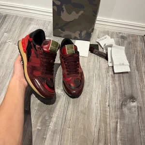 Valentino Rockrunner sneakers röd/svart - Röda valentino rockrunners i super bra skick i strl 41, passar41-42,. Allt og(box,dustbag,kvitto osv) medföljer inklusive kvitto. Självklart äkta. Perfekt nu inför vintern. Fråga vid funderingar.