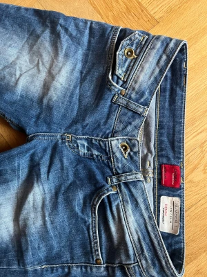 Vintage Lågmidjade bootcut blåa jeans med guld detaljer - Vintage Lågmidjade jeans från Vero Moda med guld detaljer. De var originellt slim fit men sydde om dem till bootcut (sista bilden). Syns inte alls att de är omsydda när man har på dem.