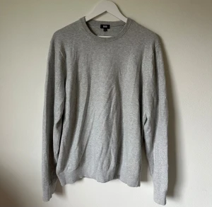 Grå bomullströja från Uniqlo - En stilren grå tröja från Uniqlo i storlek L, tillverkad i 100% bomull. Tröjan har rund hals, ribbade muddar och långärmad passform. Perfekt för dig som gillar enkel och clean stil. Passar dig som vill ha en normal passning och mjukt material. 4Ä15