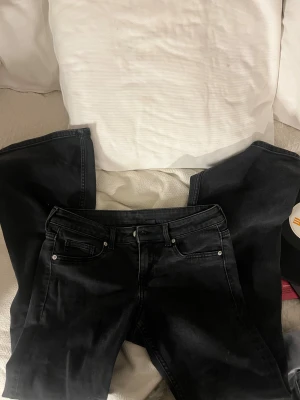 Svarta bootcut jeans med låg midja - Säljer ett par svarta jeans med bootcut och låg midja. Passformen är normal och benen är utsvängda nedtill.