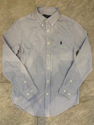Blå Ralph Lauren skjorta  - Tja! Säljer denna riktigt snygga blå Ralph lauren skjortan! Suveränt skick och är i storlek 14! Sitter som xs/S. Vid frågor så är det bara att skicka ett pm!🤗