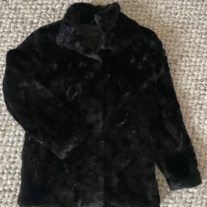 Tiger - svart pälsjacka - Superskön fuskpäls från Tiger, hög krage och lång ärm. Osynlig knäppning. Mycket sparsamt använd då jag har två snarlika pälsjackor. 