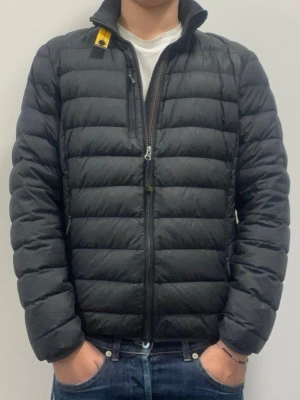 PARAJUMPERS DUNJACKA - Säljer en svart dunjacka från Parajumpers i ungdomsstorlek Large vilket motsvarar ungefär Medium i vuxenstorlek. Jackan har några år på nacken men har varit väl omhändertagen. Små defekter finns men inget som påverkar helhetsintrycket.