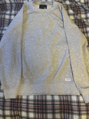 Grå sweatshirt från 157 - Säljer en enkel och stilren grå sweatshirt från 157. Tröjan har rund hals, långa ärmar och ribbade muddar vid ärmslut och nederkant. Perfekt för chill dagar och enkel att matcha med jeans eller joggers.