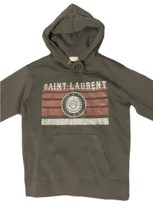 Grå Saint Laurent hoodie - Snygg grå hoodie från Saint lauren. Den är i nyskick och har bara provats 1 gång. Säljer eftersom den är för liten för mig. Tveka inte att höra av er vid frågar. Mvh Elias