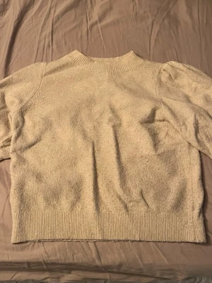 Beige stickad tröja med puffärm - Mysig beige stickad tröja med puffärm och ribbade muddar vid hals, ärmslut och nederkant. Tröjan är från Vero Moda och är i väldigt bra skick! Om man vill ha fler bilder på tröjan så får man skicka privat!💗💗