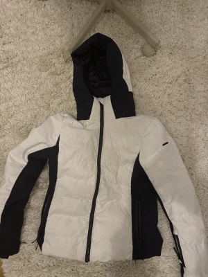 Vit och svart skidjacka från Everest - Säljer en snygg och varm skidjacka från Everest i storlek 34. Den är i riktigt fint skick förutom ett slit merke på högra arm. Normal pris är 1999kr.