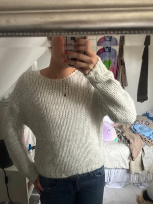 Vit stickad tröja från Zara - Mysig vit stickad tröja från Zara med grovstickad struktur och rund hals. Tröjan har lång ärm och en lite loose passform, perfekt att slänga på sig när det är kyligt. Enkel och stilren design som funkar till allt!