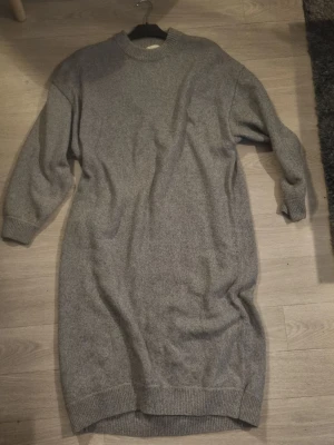 Grå stickad tröja / klänning  från H&M - Mysig grå stickad tröja mer klänning.. =)  från H&M i storlek M. Tröjan har lång ärm, ribbade muddar vid hals, ärmslut och nederkant samt en loose passform. Perfekt för kyliga dagar och enkel att styla med andra plagg.