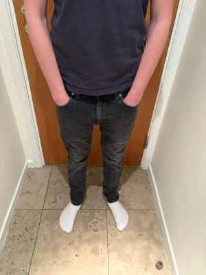 Svarta jeans från Nudie Jeans - Säljer ett par svarta slim jeans från Nudie Jeans i storlek W27 L28. Jeansen har klassisk femficksdesign, smal passform och är tillverkade i mjukt jeansmaterial. Snyggt slitna detaljer och diskreta sömmar. Perfekta till sneakers. Pris kan diskuteras 