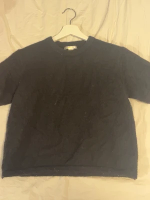 Svart stickad tröja Gina Tricot - Svart stickad tröja från Gina Tricot med rund hals och korta ärmar. Mjuk och skön känsla, perfekt för lager-på-lager under kyliga dagar. Passar dig som gillar enkel och stilren look.