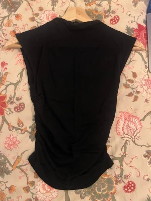 Svart topp från Gina Tricot XS - Säljer en svart topp från Gina Tricot i storlek XS. Toppen har en enkel och stilren design med korta ärmar och rund hals. Materialet känns mjukt och lätt, perfekt för att matcha med jeans eller kjol. Snygg basic som funkar till många olika looks.