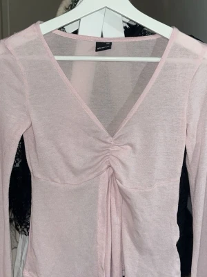Ljusrosa topp med knytning Gina Tricot - Supersöt ljusrosa långärmad topp från Gina Tricot med v-ringning och snygg snörningsdetalj framtill. Tunn och mjuk i materialet, perfekt för vår och sommar. Använd några gånger så något nopprig men annars fint skick! 🌸💕