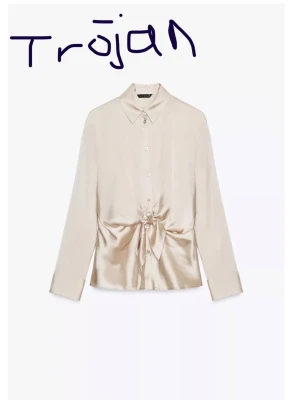 Zara satin shirt with knot -  Elegant beige topp i satinliknande material med knytdetalj framtill. Använd endast en gång och köptes i Italien för 370kr. Skjortmodell med knappar och långa ärmar som ger en stilren och feminin look. Endast använd en gång – i mycket fint skick. Perfekt till både vardag och fest.