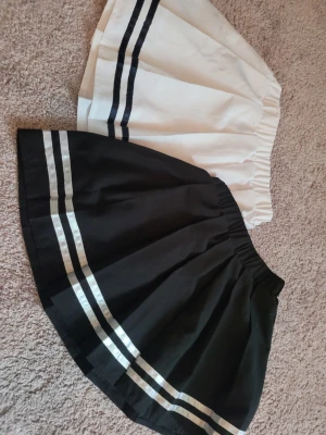 Coola kortkjolar - Säljer två korta kjolar med sportig look, en svart med vita ränder och en vit med svarta ränder, båda med resår i midjan. Dessutom en svartvit rutig kjol med klassiskt rutmönster. Perfekt för dig som gillar att mixa stilar och vill ha något som sticker ut. Sälj som paket om 3 st.