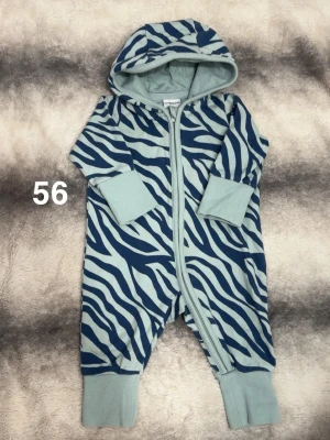 Blå zebramönstrad byxdress med huva - Säljer en blå och ljusblå byxdress från Polarn o pyret med zebramönster och huva. Dressen har muddar vid ärmar och ben samt dragkedja framtill för enkel påklädning. Perfekt för chill dagar hemma eller när du vill sticka ut lite extra.🌸 Fint använt skick. Storlek 56.