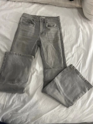 Grå jeans från Denim Day, storlek 158 - Snygga grå jeans från Denim Day i klassisk femficksmodell. Jeansen har raka ben och normal passform, med bälteshällor och knappstängning. Materialet är mjukt denim i bomull och de har en stilren look som funkar till många outfits.