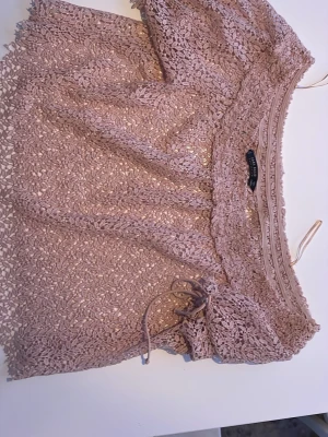 Beige spetsblus med snörning - Säljer en beige blus från Zara i spets med fina virkade detaljer. Toppen har offshoulder-modell och snörning framtill för extra detalj. Perfekt till sommaren och ger en romantisk vibe.
