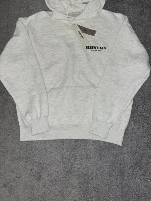 Essentials hoodie  - Säljer en helt ny grå Essentials hoodie. Den kommer med taggarna och essentials påsen. Hoodien har storleken XS men passar också S. Om du har frågor eller något bud så är det bara att skriva till mig.