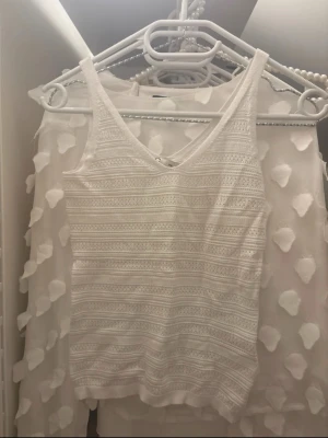 Vit stickad linnetopp från Cubus - Säljer en vit stickad linnetopp från Cubus i storlek XS. Toppen har ett snyggt mönster med horisontella ränder och är ärmlös med v-ringad hals. Perfekt för varma dagar och enkel att matcha med jeans eller kjol.