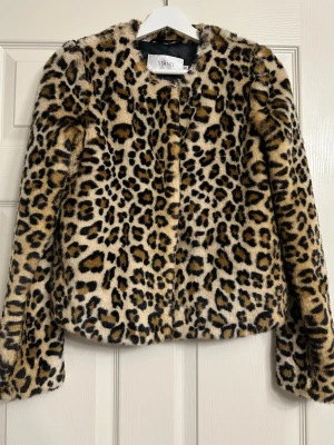 Leopardmönstrad pälsjacka från Stand - Säljer en supercool pälsjacka från Stand med leopardmönster. Jackan är fluffig och har en rak, lite boxig passform med långa ärmar. Perfekt statement-plagg för dig som vill sticka ut. Fodrad och riktigt mjuk!