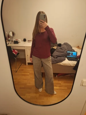 Vinröd långärmad topp - Säljer en vinröd långärmad topp från Queentex i storlek M. Toppen har en liten rosett framtill vid halsringningen och är gjord i mjuk bomull. Passformen är normal och modellen är enkel med rundad hals. Perfekt att styla med jeans eller kjol. Passar även S.