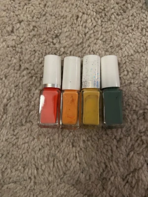 Fyra nagellack från Depend - Säljer fyra nagellack från Depend i snygga färger: klarröd, orange, gul och mörkgrön. Flaskorna är rektangulära med vita lock och tydlig Depend-logga. Perfekt för dig som vill ha färgglada och trendiga naglar.