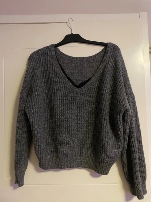 Grå stickad tröja från Vila XL - Mysig grå stickad tröja från Vila i storlek XL. Tröjan har en djup v-ringad hals och ribbad struktur som ger en cool och avslappnad vibe. Perfekt att slänga på sig när det är kyligt ute. Långa ärmar och loose passform.